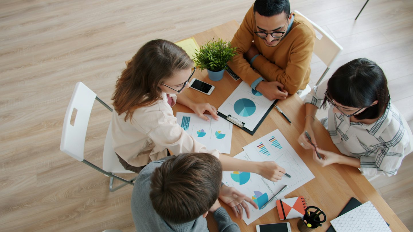 Para profesional bisnis berkolaborasi di sekitar meja dengan dokumen.