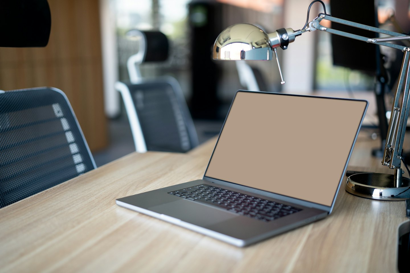 Laptop modern di atas meja kayu terang.