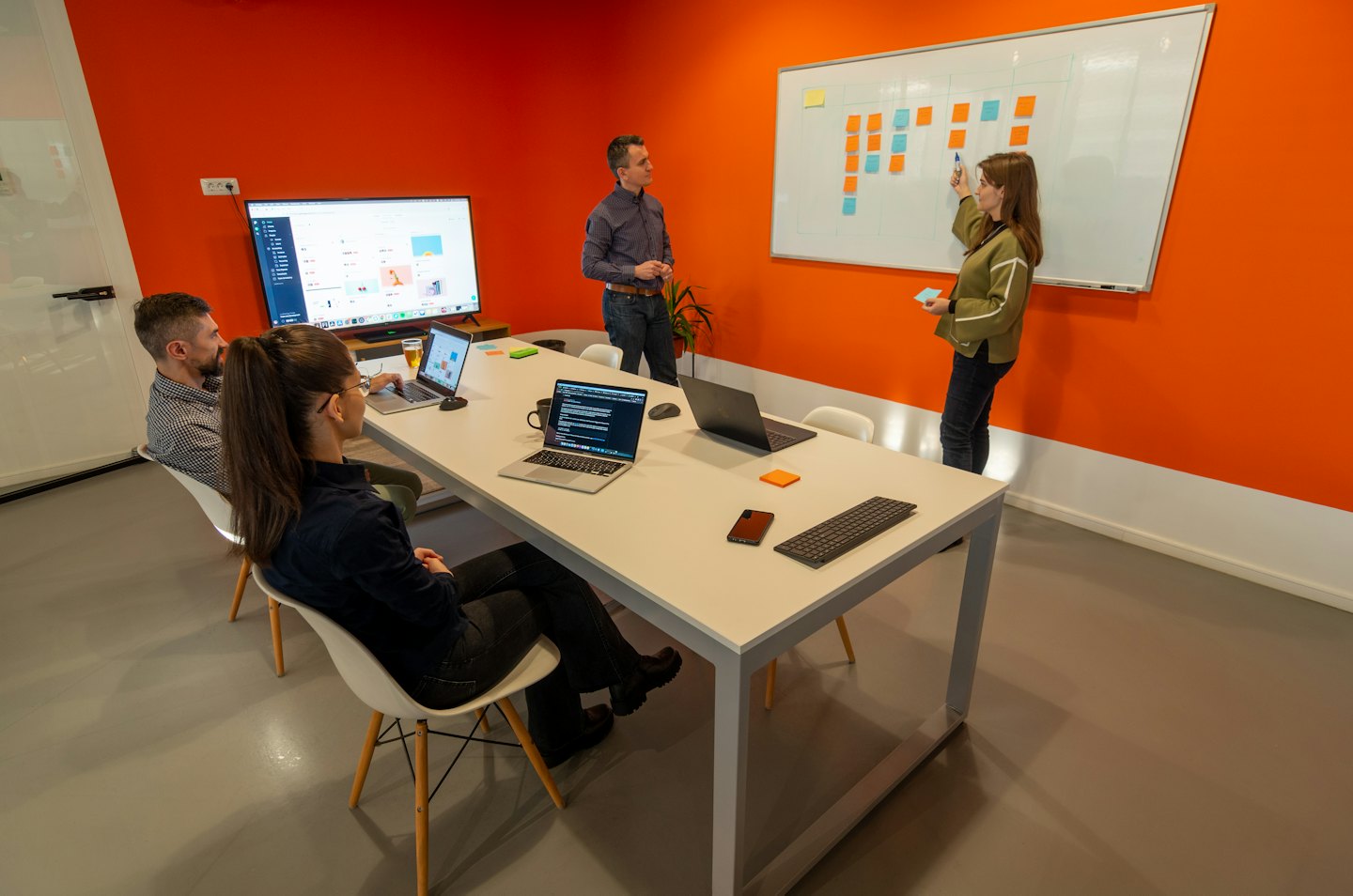Tim berkolaborasi di kantor modern dengan aksen oranye.
